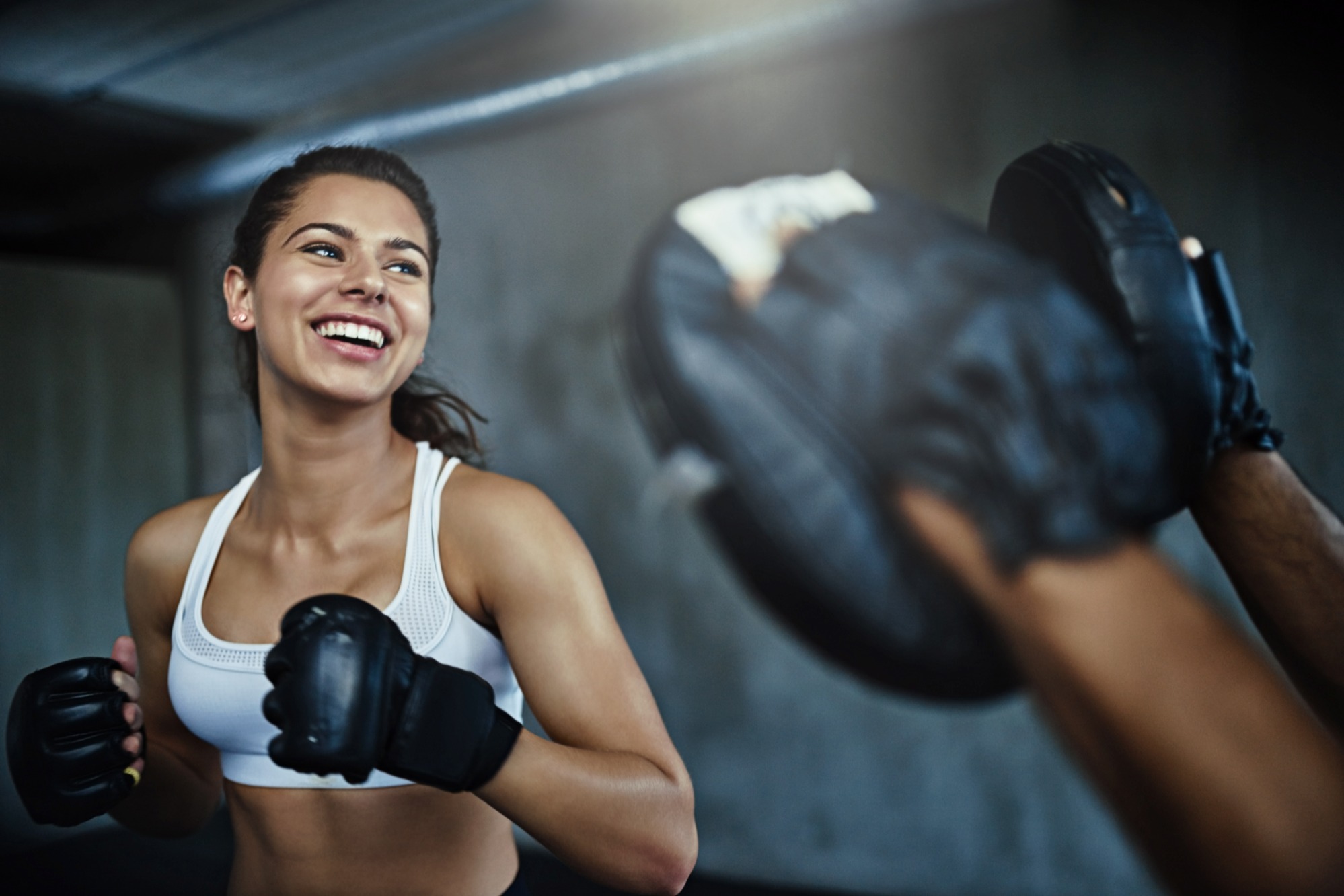 Woman-smiling-while-practising-boxing-with-a-trainer